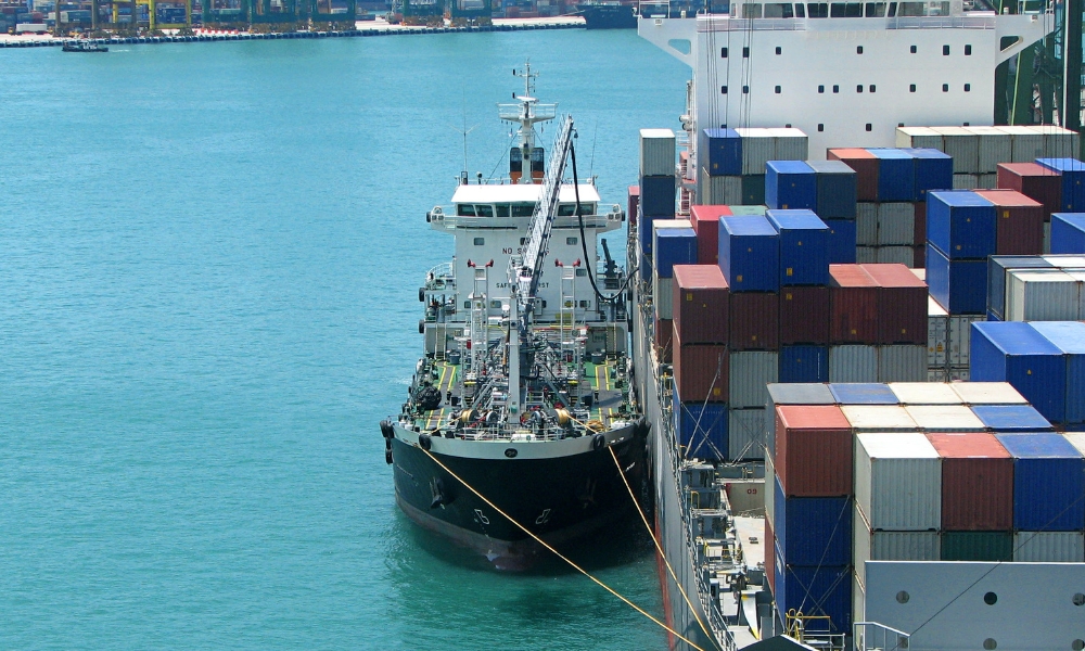 Bunker Holding:Bunker tanker vessel supplying marine fuel to a cargo ship at anchorage